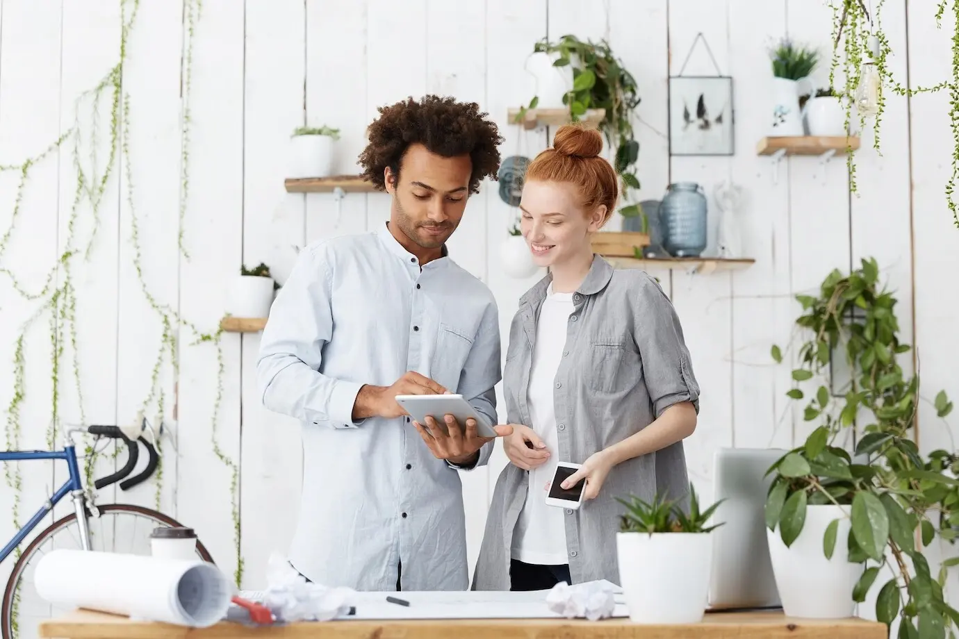 Junges Ehepaar gemischter ethnischer Herkunft, das die Baupläne für sein zukünftiges Haus entwirft.